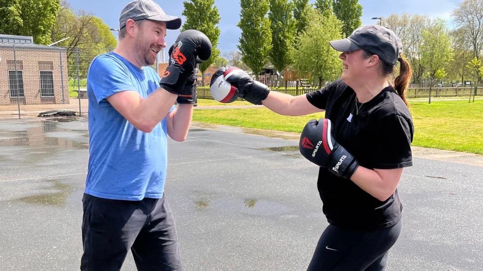 A man and woman practicing boxing drills during an outdoor personal training session at Jubilee Park Leyton